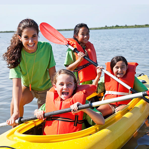 3 kids and a adult supervisor learning to kayak